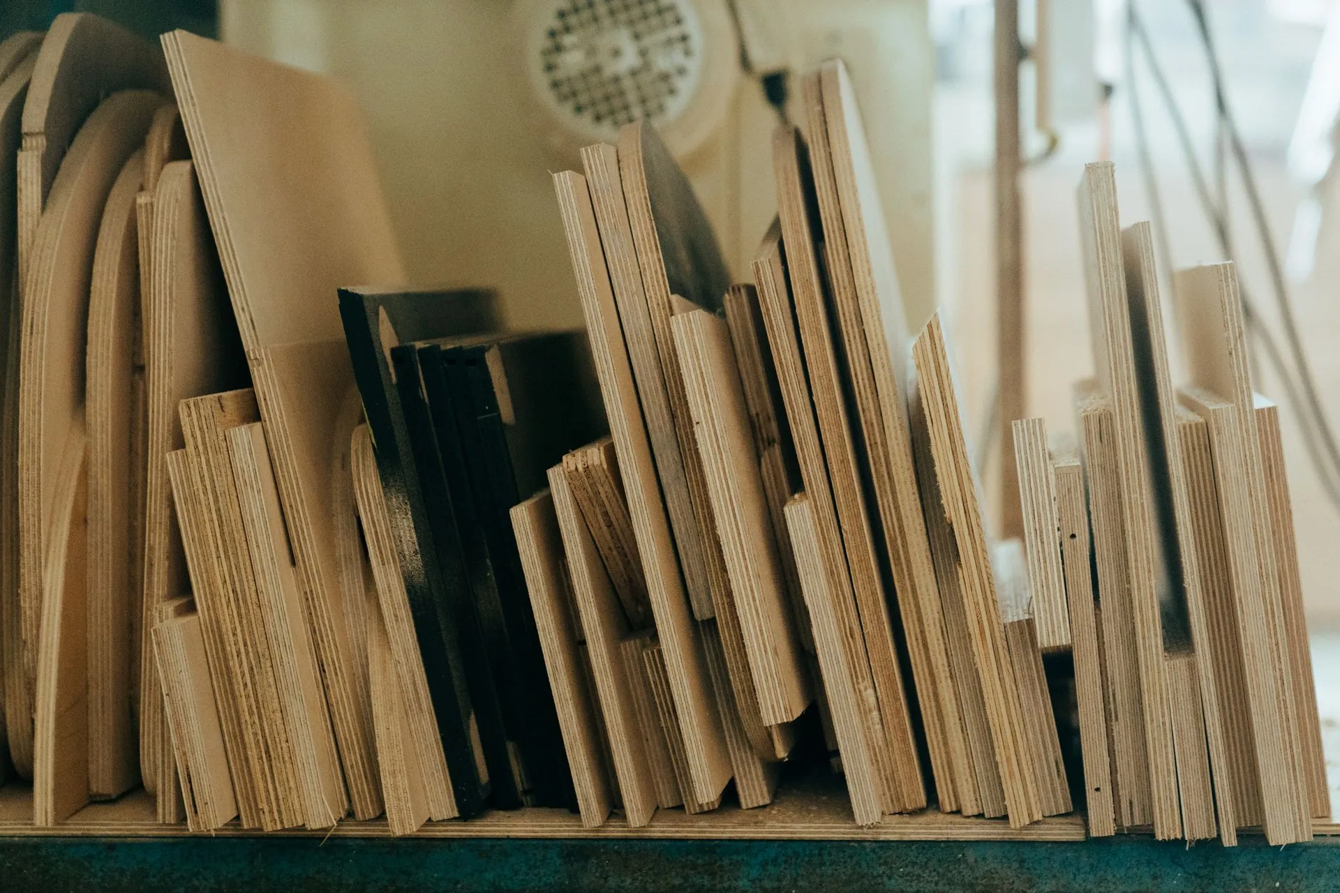 Offcuts of plywood and board standing on edge in a workshop, the layers inside each sheet showing.